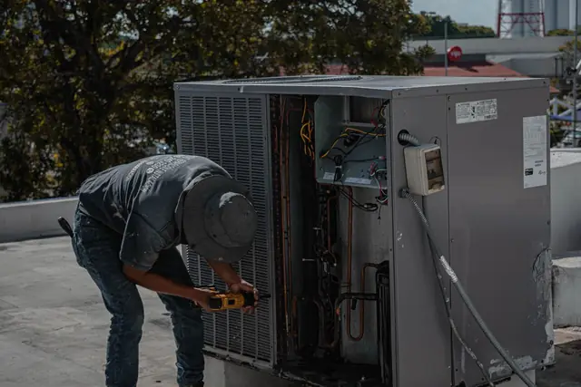 Technician checking the electrical panel inside an outdoor AC unit